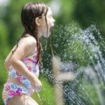 girl playing in sprinkler x
